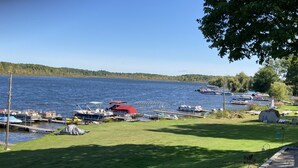 A lakeside dock with boats, a grassy area, and a small shed.