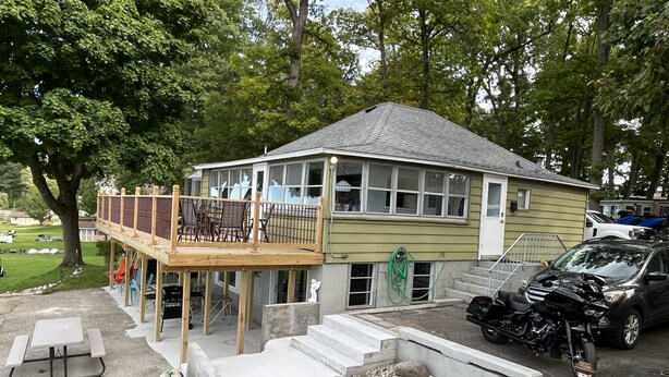 A house with a deck, a patio, and a garden area with a birdbath.