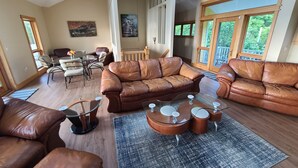 Ein geräumiges Wohnzimmer mit Ledersofas, einem Glastisch und einem Essbereich mit Tisch und Stühlen.