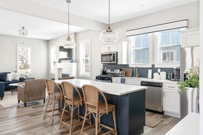 A modern kitchen with a central island, white cabinetry, and a large window. - Brand New Luxury Home less than a mile from Notre Dame (South Bend)