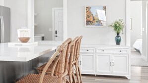 Une cuisine moderne avec un îlot central blanc, des chaises en osier et un meuble blanc.