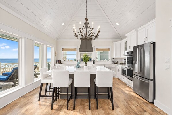A modern kitchen with a central island, stainless steel appliances, and a view to the outside.