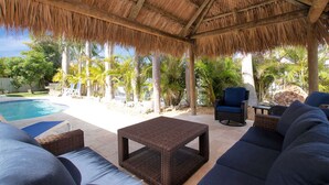 A covered outdoor area with a pool, lounge chairs, and a ceiling fan. - Fisherman's dream!!, Privacy, Heated Pool,Hot Tub, 50' Dockage, Tiki, pets ok,   (Marathon)