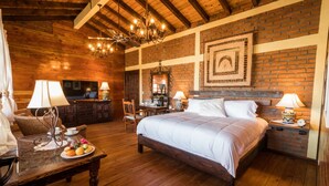 A cozy room with a large bed, wooden floors, a brick wall, a chandelier, and a television. - Suite Giuseppe, luxury and comfort close to the malecon. Breakfast included  (La Paz)