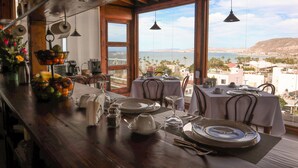 A dining area with a view of the sea, wooden furniture, and a table set for two. - Suite Giuseppe, luxury and comfort close to the malecon. Breakfast included  (La Paz)