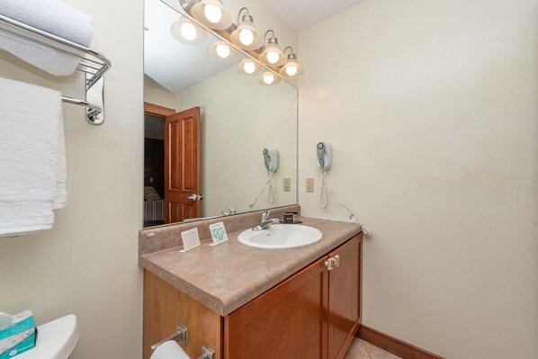 A bathroom with a white sink, wooden vanity, and a mirror with lights.