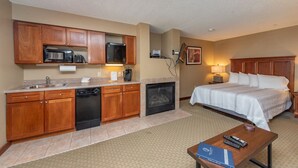 Hotelkamer met kitchenette, een bed, nachtkastje met afstandsbediening en een lijst aan de muur.