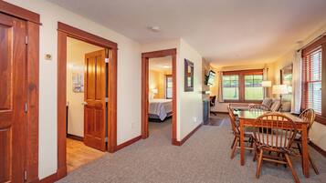A hotel room with a wooden dining table, chairs, a bed, and a bathroom visible through an open door.