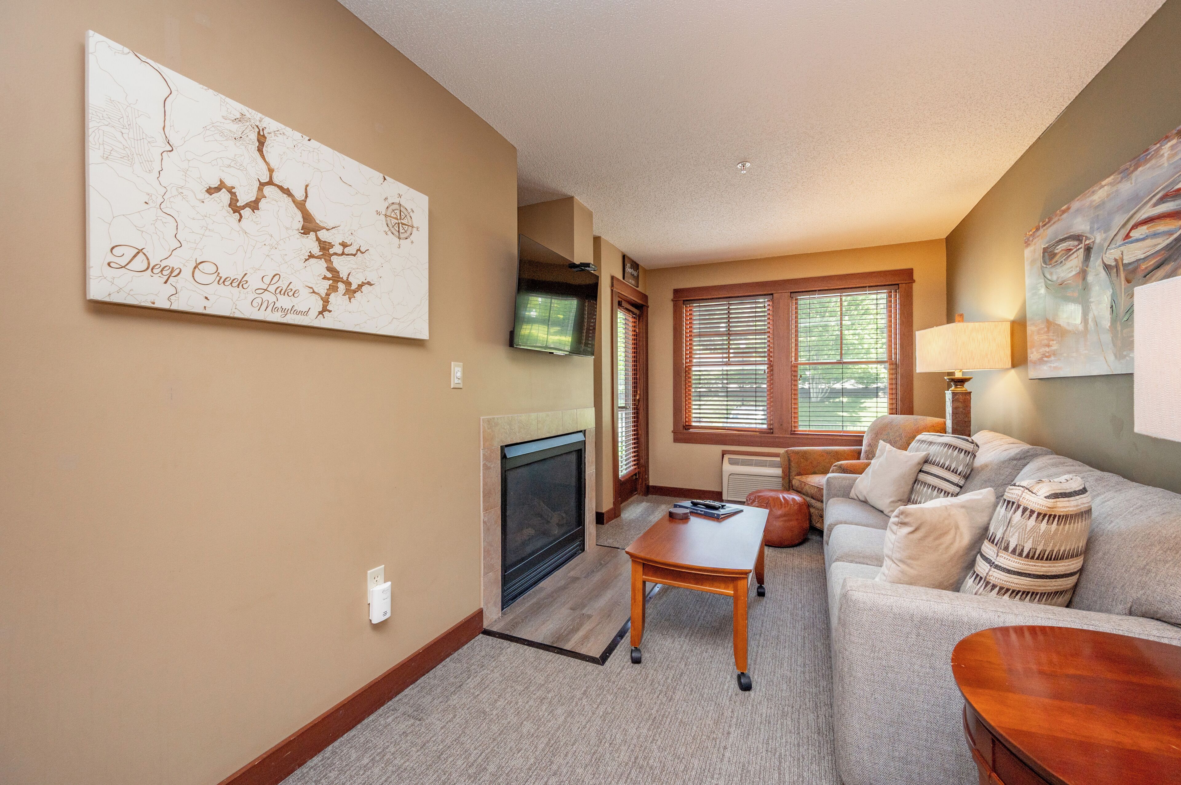 A living room with a fireplace, a sofa, a coffee table, and a map on the wall.