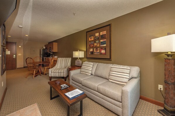 A living room with a sofa, armchairs, a coffee table, and a dining area with a table and chairs.