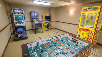 Een kamer met een tafelvoetbaltafel, twee speelautomaten en een grijpkraan.