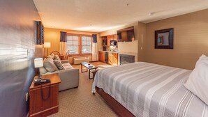 A hotel room with a bed, a sofa, a desk, a television, and a kitchenette. - Suites at Silver Tree: A210 Studio Standard View (Oakland)
