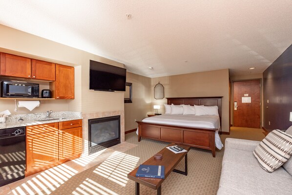 Une chambre d’hôtel comprenant un lit, une télévision, un coin cuisine et un espace salon.