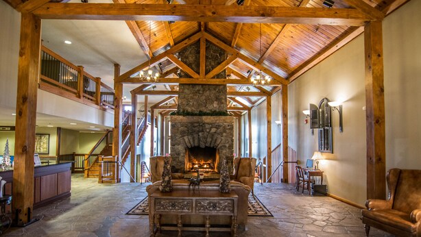 A spacious lobby with a stone fireplace, wooden beams, and a high ceiling. - Suites at Silver Tree: A213 Studio Lake View (Oakland)