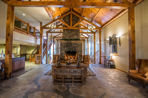 Cozy gathering space with a stone fireplace, reception desk, and staircase.