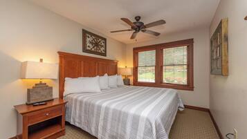 A bedroom with a bed, nightstand, lamp, ceiling fan, and window with blinds.