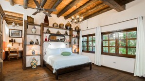 A wooden-floored bedroom with a bed, a chandelier, and a large window with curtains. - Suite Leonardo, luxury and comfort close to the malecon. Breakfast included (La Paz)