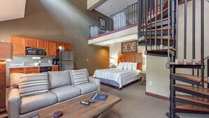 A hotel room with a kitchenette, a sofa, a bed, and a staircase. - Suites at Silver Tree: A304 Studio & Loft Standard View (Oakland)