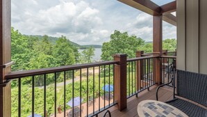 A balcony with a wooden railing, a view of a lake, and outdoor furniture. - Suites at Silver Tree: A311 One Bedroom & Loft Lake View (Oakland)