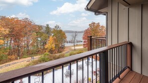 Een balkon met uitzicht op een meer en herfstbomen.