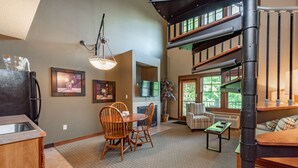 A spacious living area with a dining table and chairs, a fireplace, and a staircase leading to an upper level. - Suites at Silver Tree: B206 One Bedroom & Loft Lake View (Oakland)