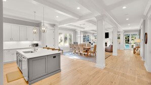 A spacious kitchen with a central island, white cabinetry, and a large dining area with wicker chairs.