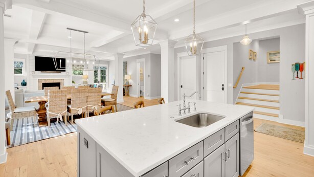 A modern kitchen with a large island, grey cabinetry, and pendant lighting.