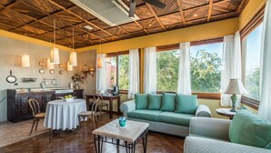 A cozy room with a wooden ceiling, a dining area with a table and chairs, a sofa, and large windows offering a view of greenery outside. - Beautiful Suite with kitchen Stefano, comfort close to the malecon (La Paz)