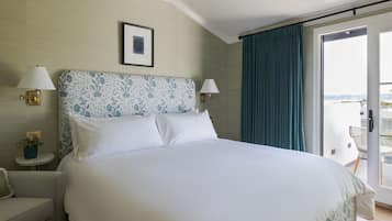 A hotel room with a large bed, two bedside lamps, a framed picture on the wall, and a view through a sliding door.