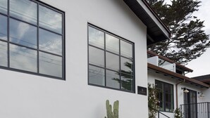 Una casa moderna con una fogata, plantas en macetas y un banco.