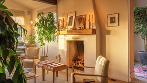 Una sala de estar acogedora con chimenea, asientos cómodos y plantas en macetas.