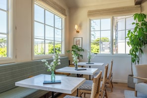 A restaurant with large windows, wooden benches, and tables with vases of flowers.