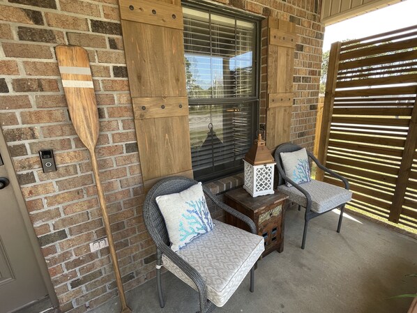A patio with wicker chairs, a wooden table, and a lantern.