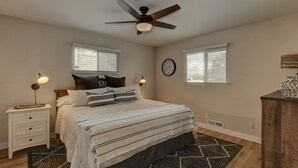 A bedroom with a bed, two bedside tables, a ceiling fan, a clock, and two windows with blinds. - **Newly Remodeled Home** 1 mile from Prescott Courthouse! (Prescott)