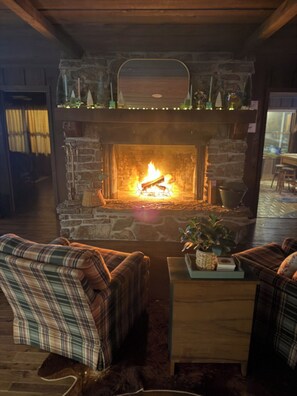 A cozy room with a stone fireplace, plaid furniture, and a wooden coffee table.
