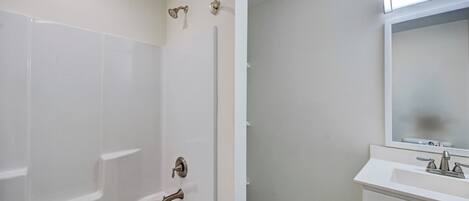 A bathroom with a bathtub, a shower, and a sink with a mirror.