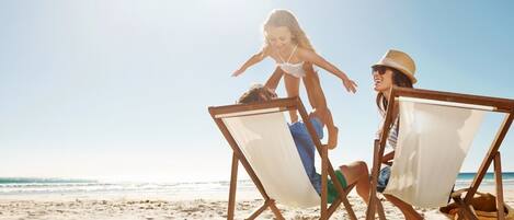 A beach scene with two beach chairs and a person sitting in one.