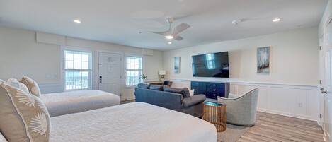 A bedroom with two beds, a sofa, a TV, and a ceiling fan.