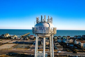 A water tower with the word "SURF" on it, surrounded by houses and a beach.