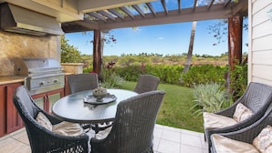 Un patio al aire libre con una parrilla, sillas de mimbre y vistas del paisaje.