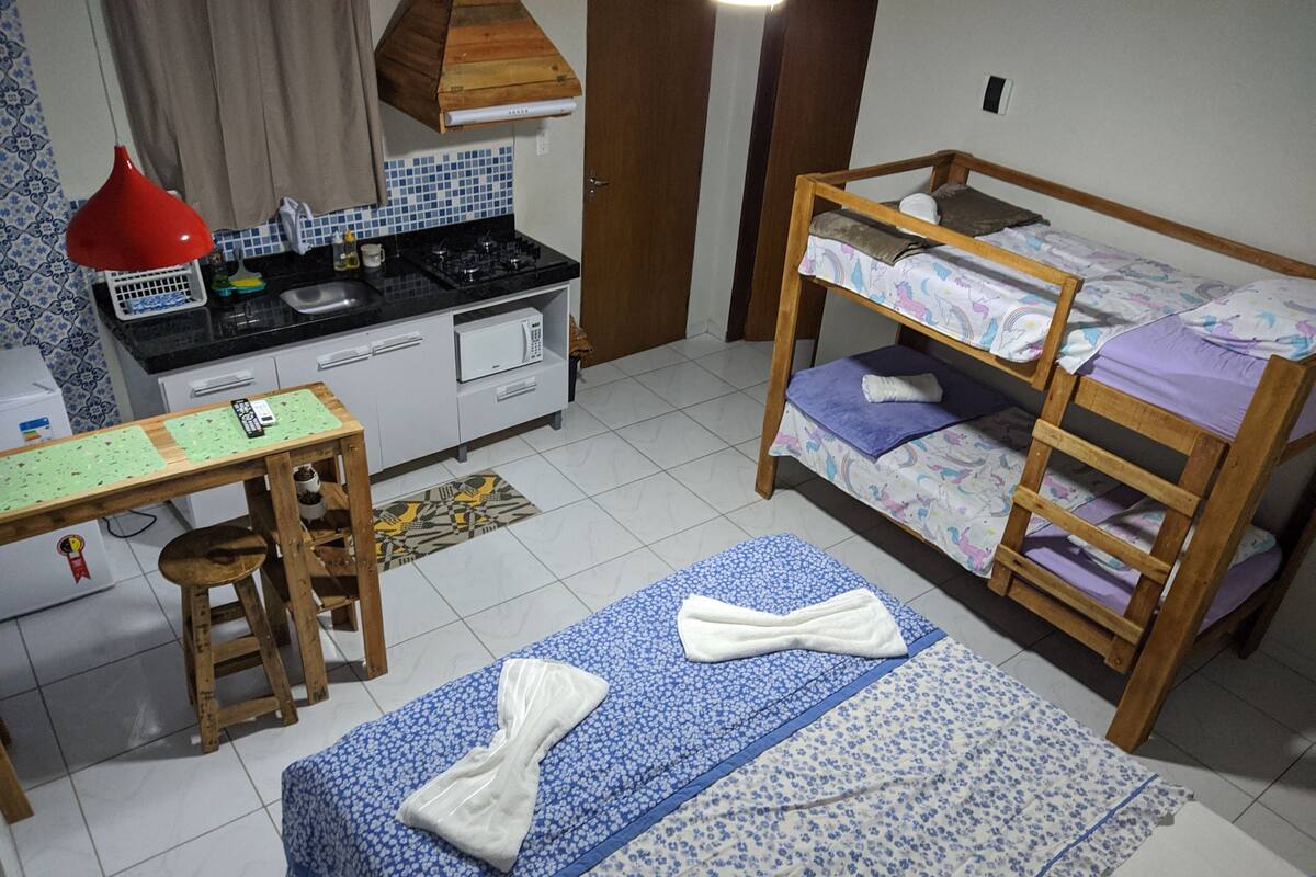 A room with a kitchenette, a desk, a bunk bed, and a patterned rug.