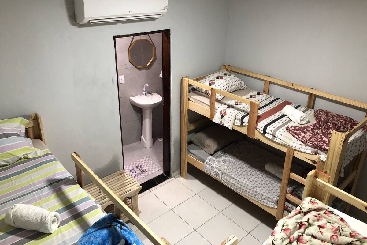 A dormitory room with bunk beds, a sink, and an air conditioning unit.