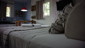 Un dormitorio con una cama, una lámpara colgante roja y un ventanal con cortinas.