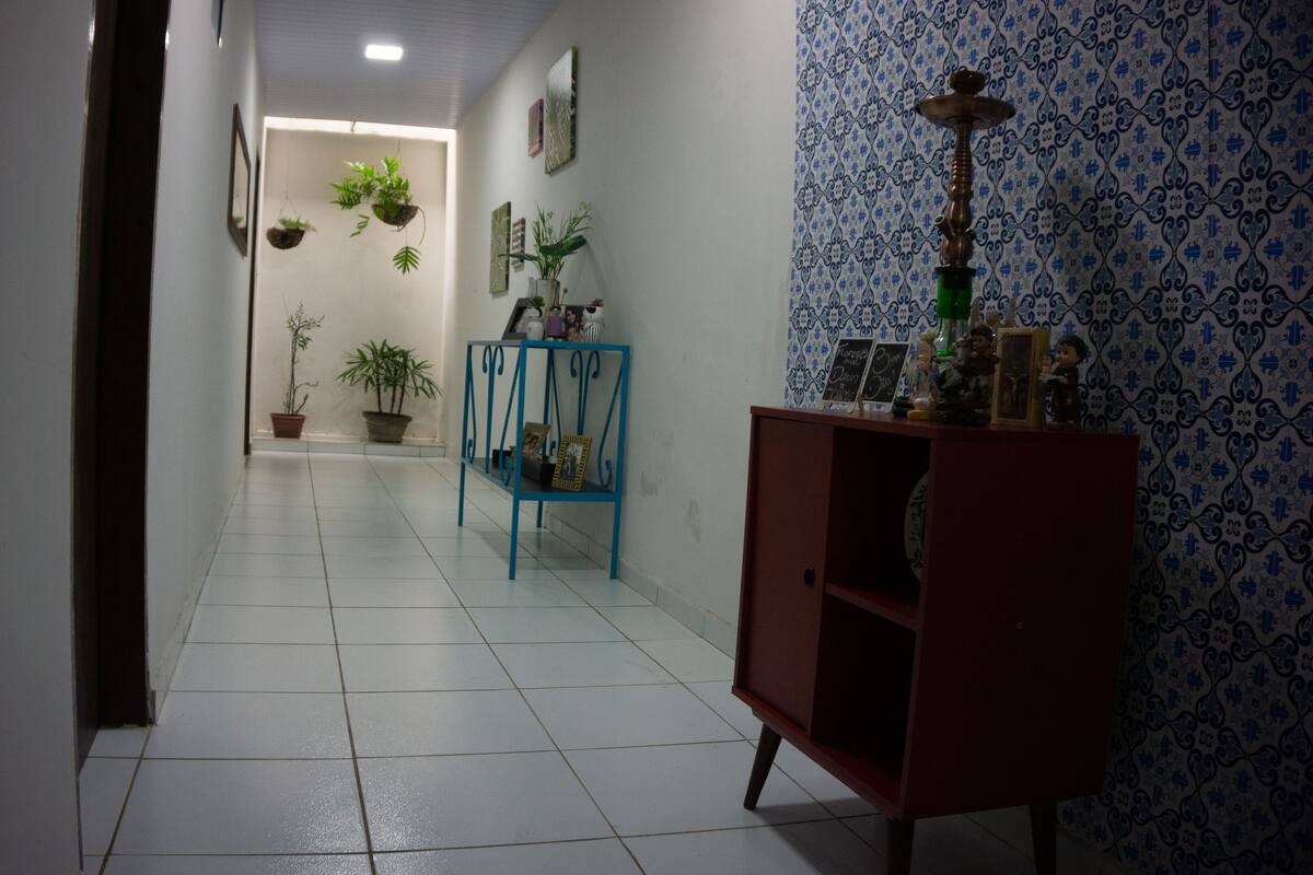 A hallway with a tiled floor, a blue metal console table, and a red cabinet.