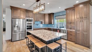 Una cocina moderna con armarios de madera, electrodomésticos de acero inoxidable y una isla de mármol con taburetes.