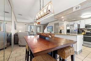A modern kitchen with a wooden island, stainless steel appliances, and a large chandelier.