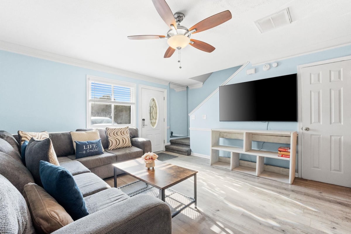 Un salon comprenant un canapé, une table basse, un téléviseur et un ventilateur de plafond.