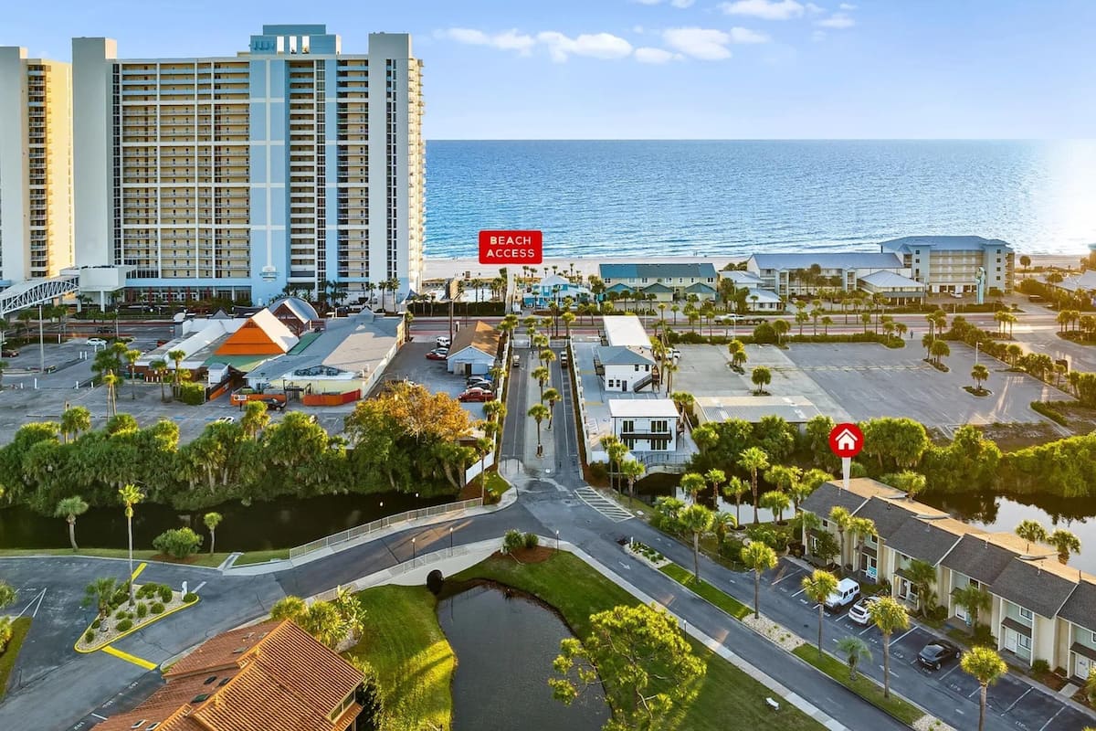 Un hôtel situé sur la côte, avec un panneau indiquant l’accès à la plage, un parking et une vue sur l’océan.
