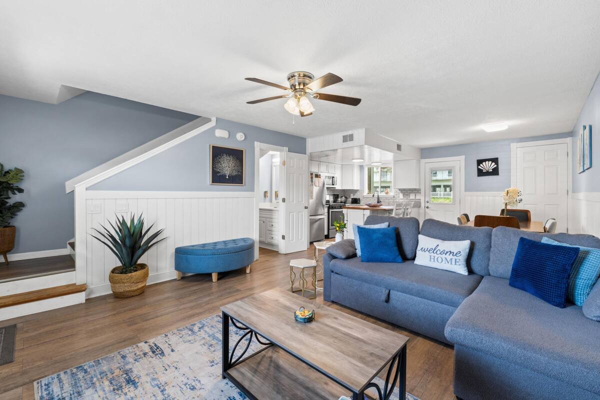 Un salon moderne avec un canapé bleu, une table basse et un ventilateur de plafond.