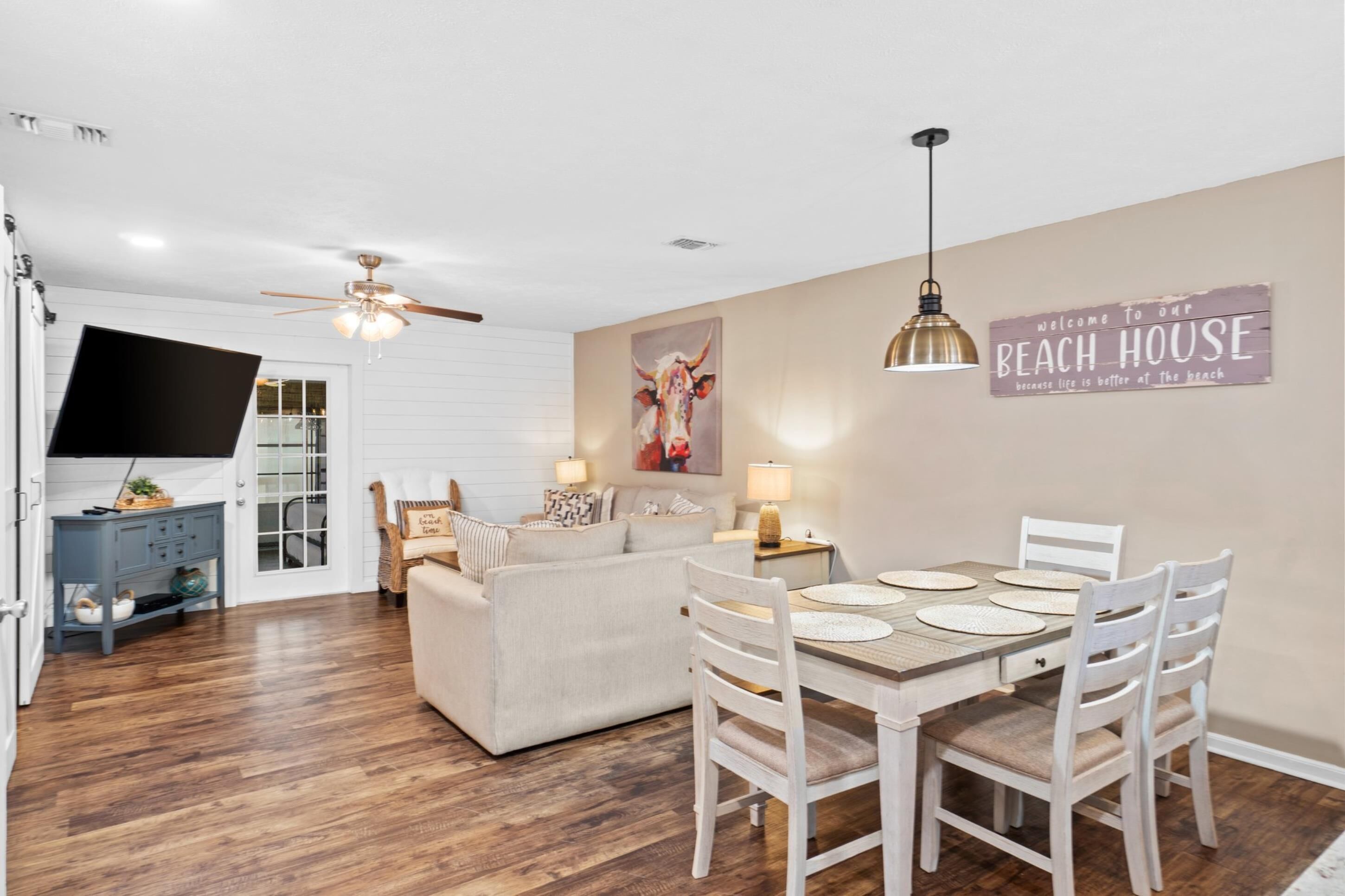 A dining area with a table set for four, a sofa, and a television in the background.